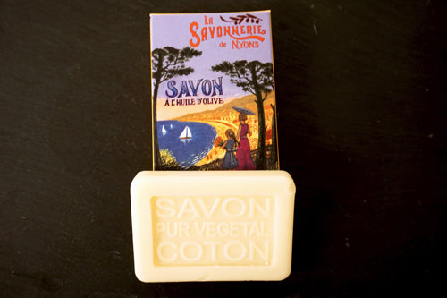 25 gram Rektangulärformad gästtvål från Frankrike. Krämvit av doften bomullsblomma. Liggandes under medföljande kartong med motiv på: Två personer som blickar ut över sjön under nattid.